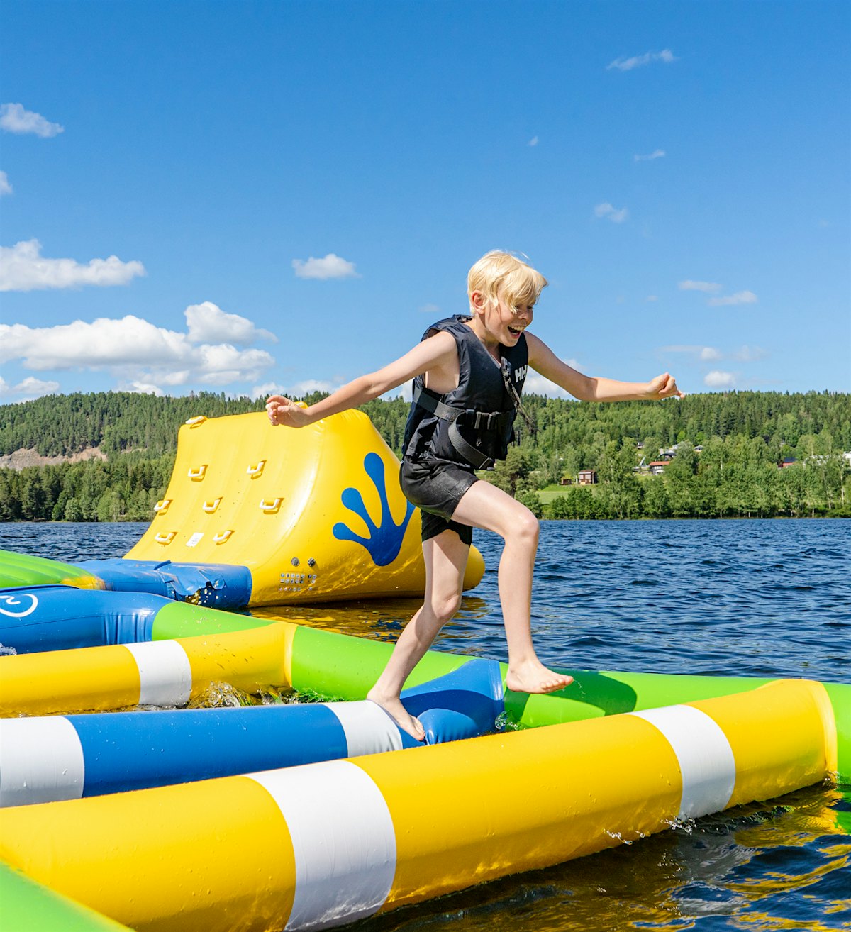 Boy runs smiling across a floating water park. Photo