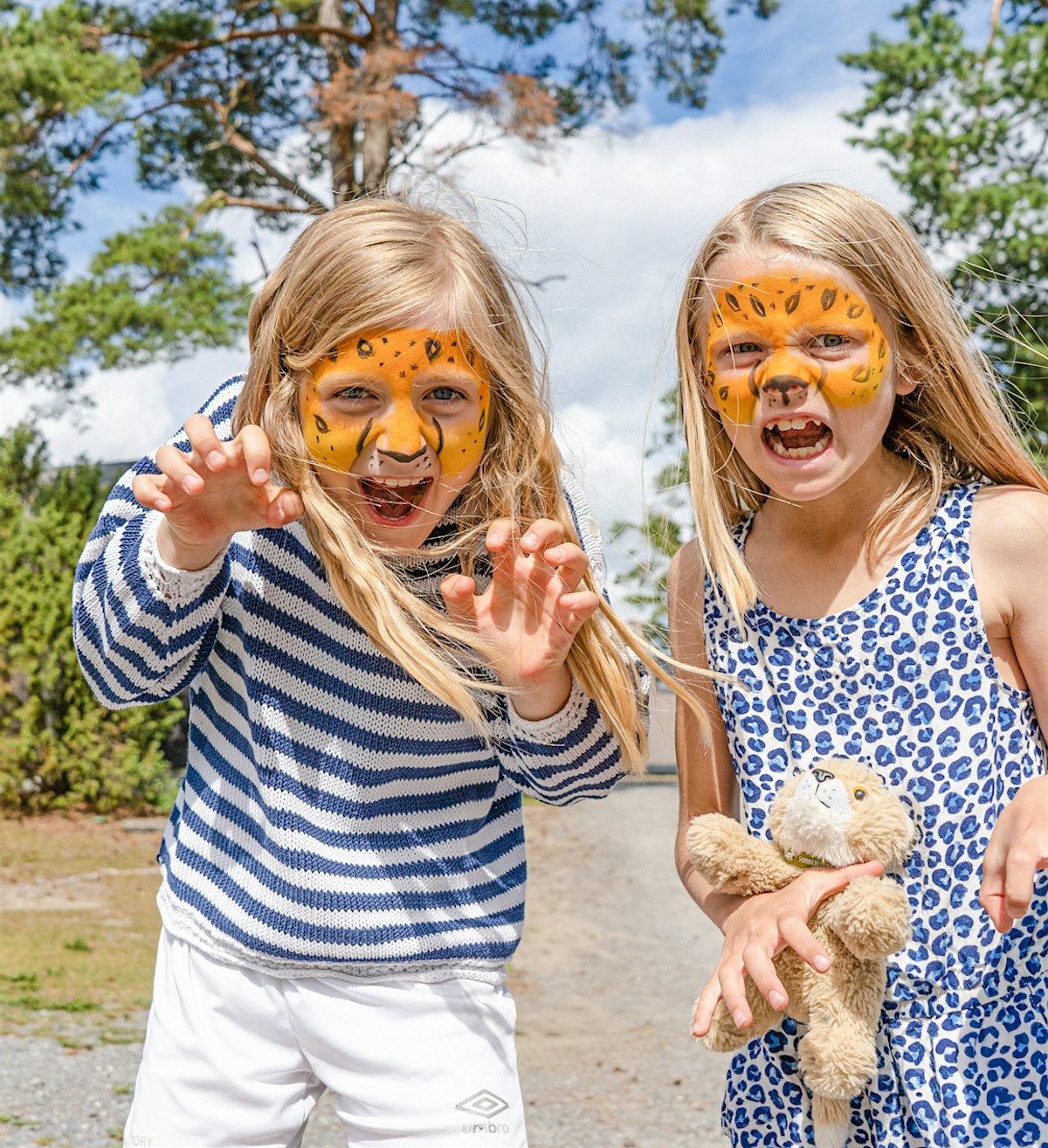Zwei Mädchen haben ihre Gesichter als Leoparden anmalen lassen. Leopardengesichter für die Kamera machen. Foto