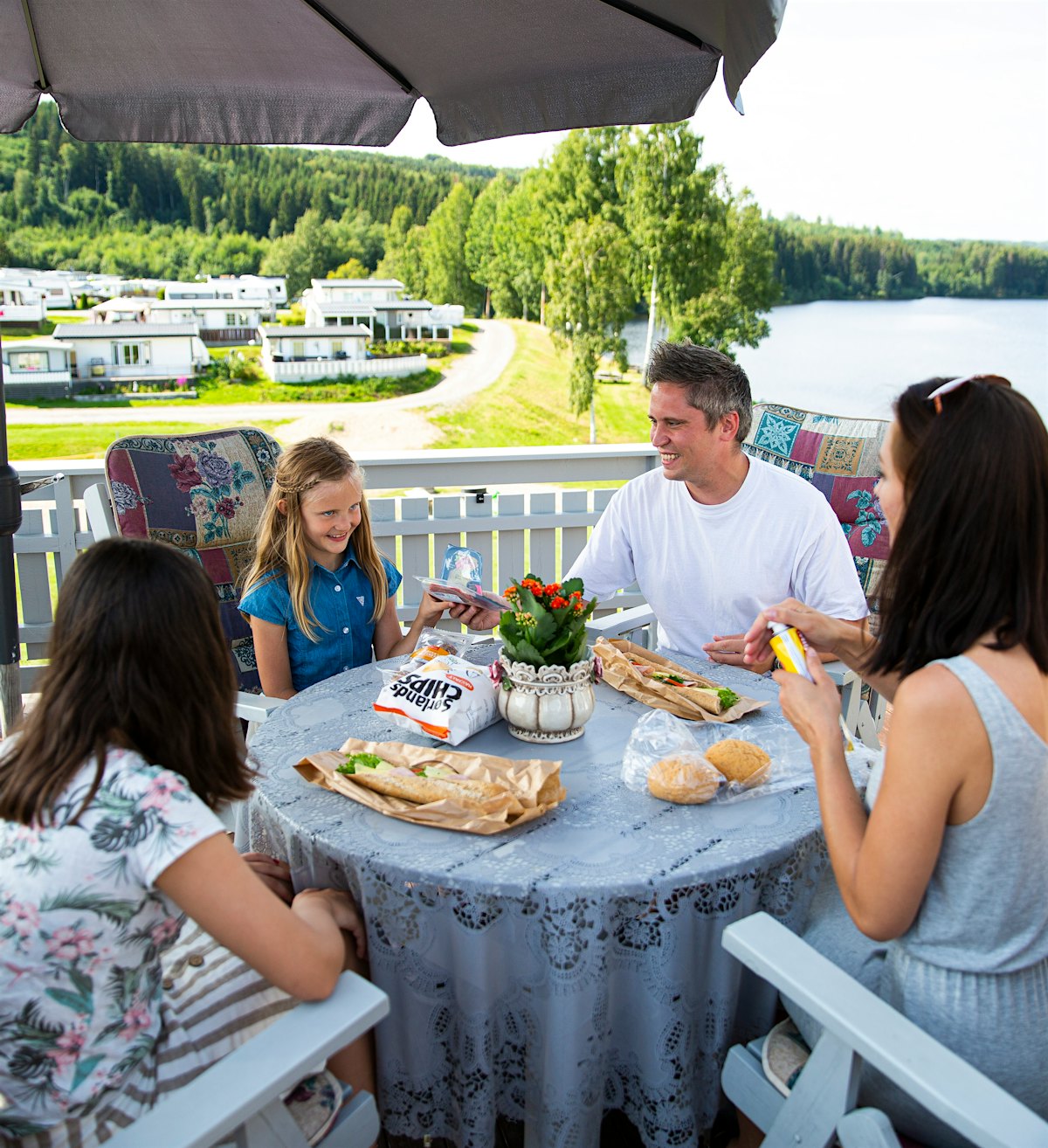 Die Familie isst zu Mittag auf der Terrasse des Camping-Saisonplatzes mit Blick auf Mjøsa