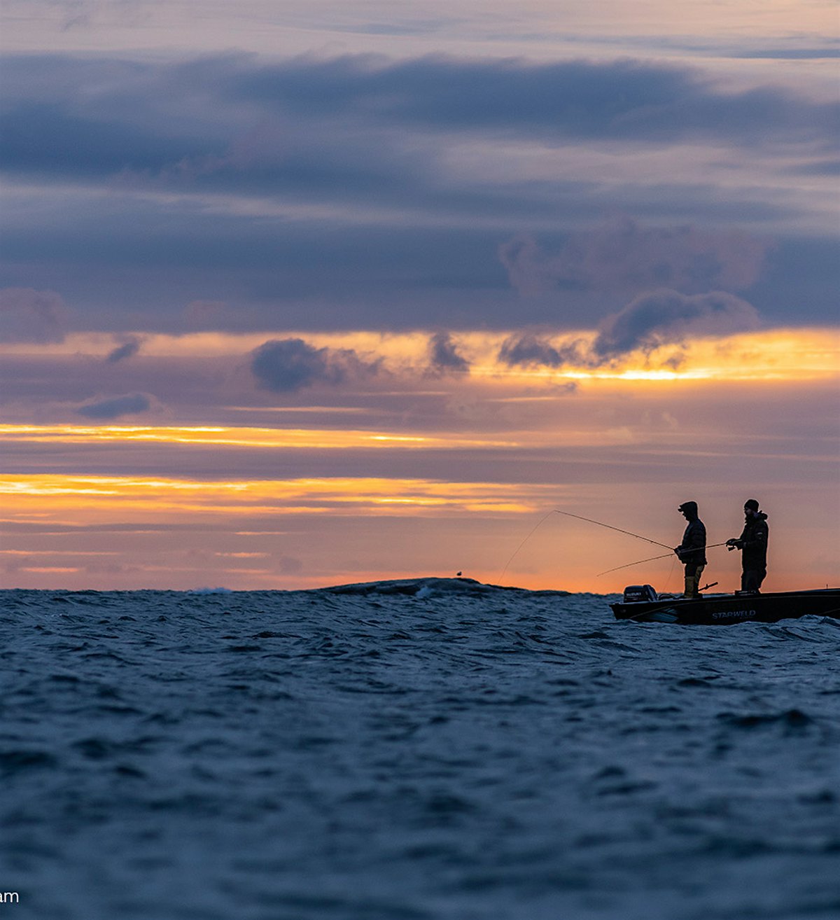 Liten båt på havet, med to fiskere i solnedgang.