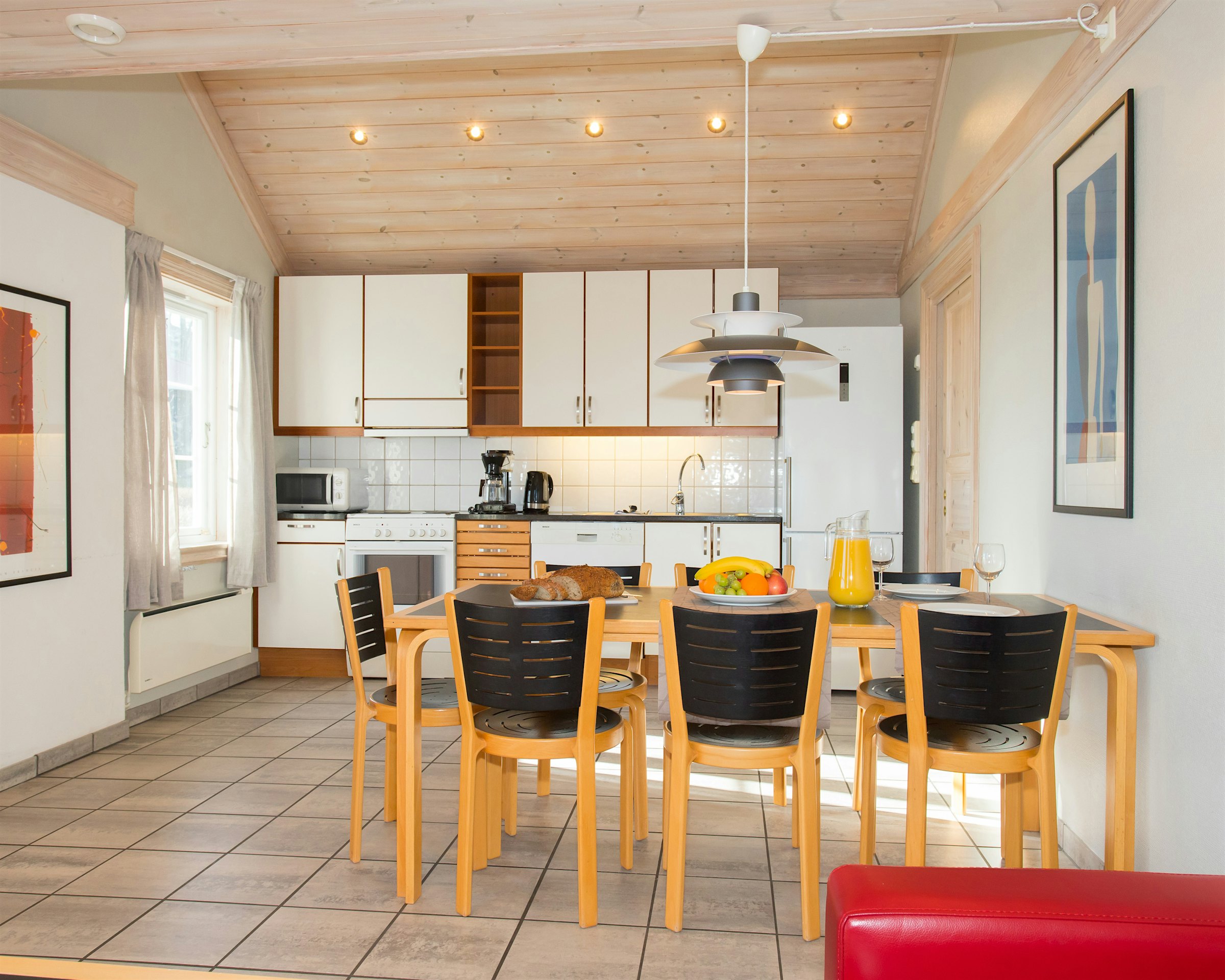 Großer offener Raum mit Küche und Esstisch. Der Tisch ist mit Obstplatten, Brot und Getränken gedeckt. Foto