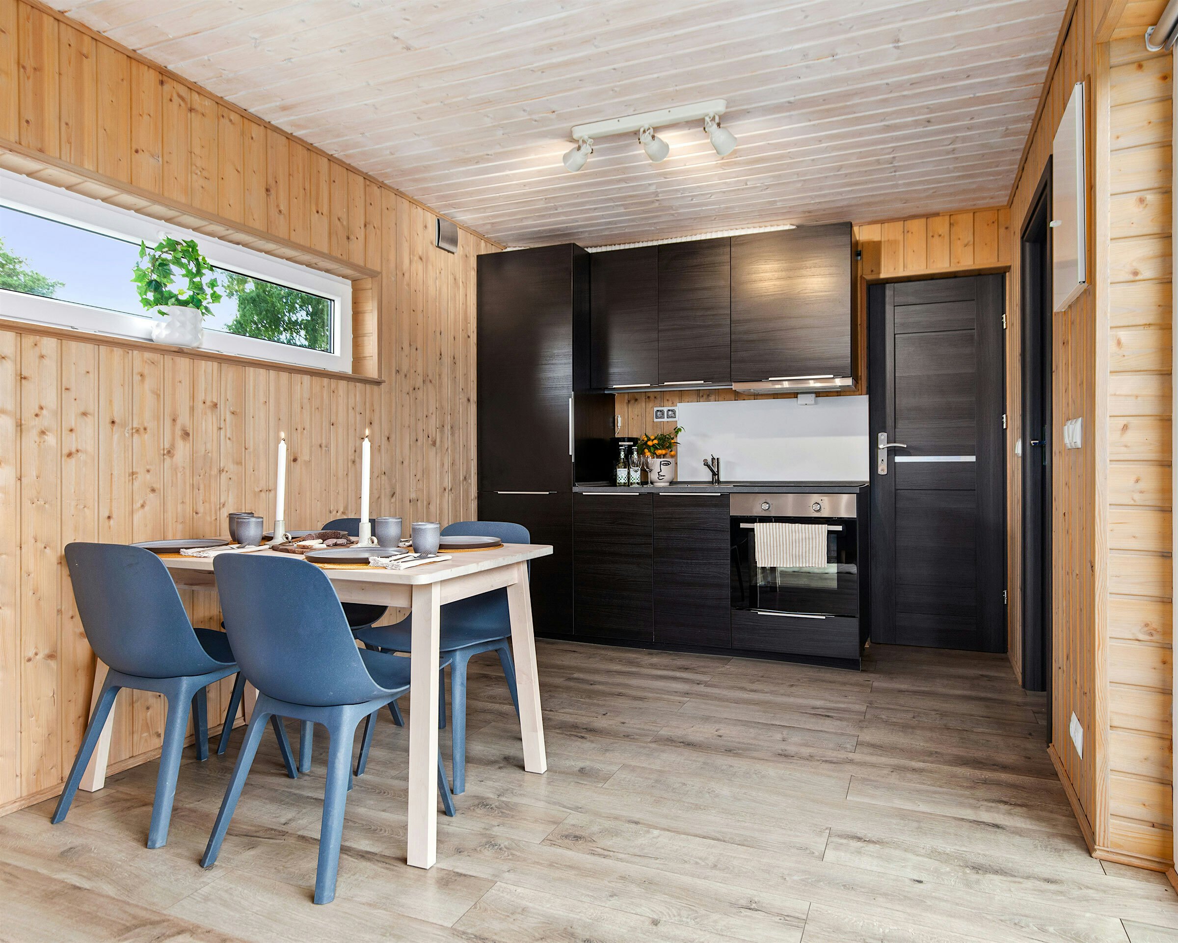 Moderne rom med dekket spisebord, kjøkken med kjøleskap og komfyr i bakgrunnen. Foto