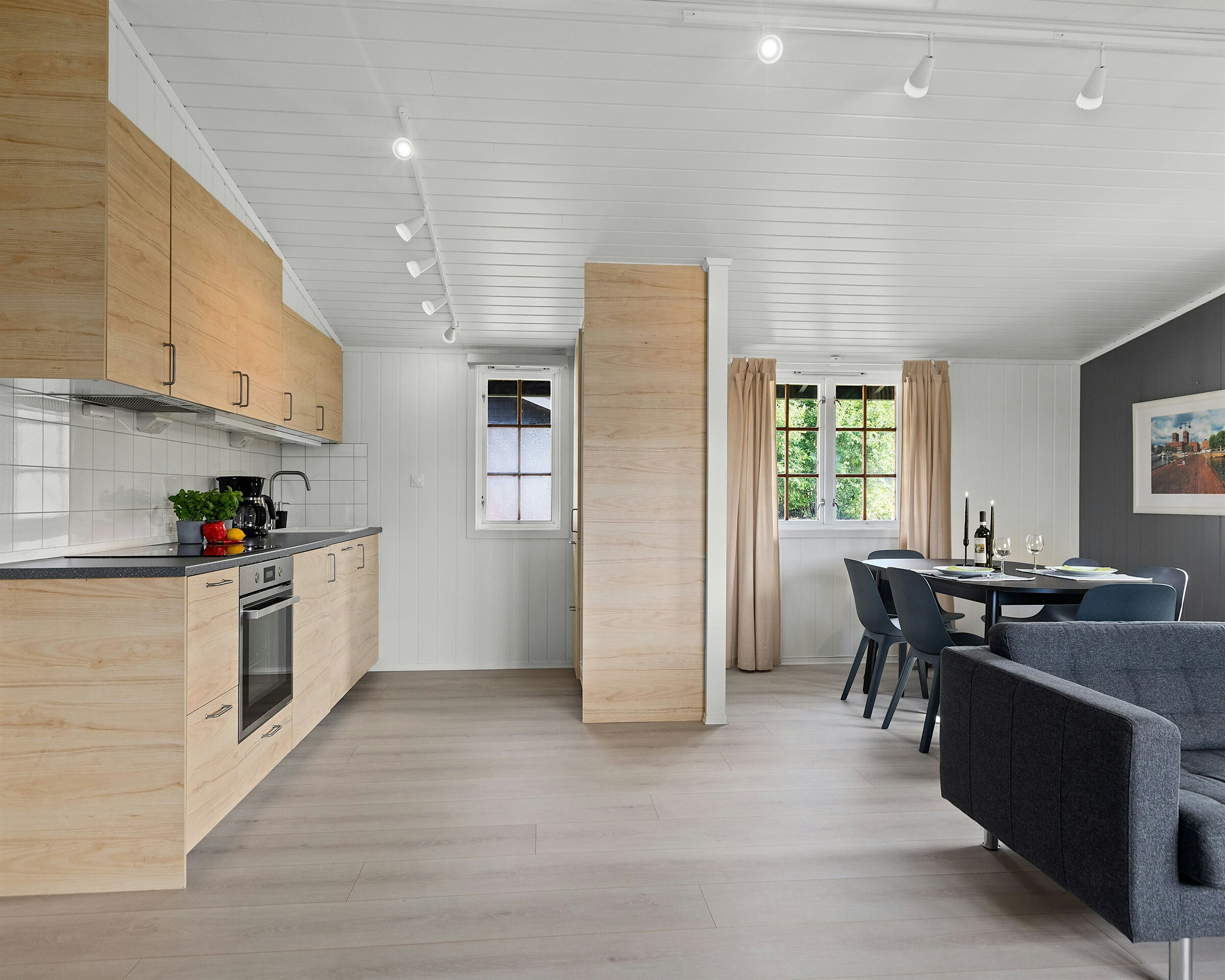 Moderne rom med kjøkken, spisegruppe og sofa. Foto