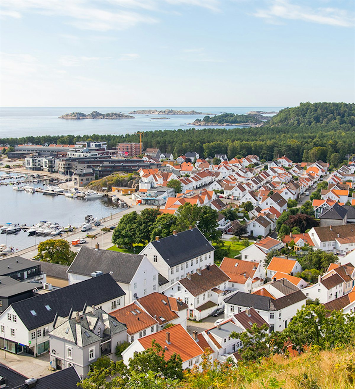 Oversiktsbilde over Mandal med mange hvite trehus, havnen og Furulunden. Foto