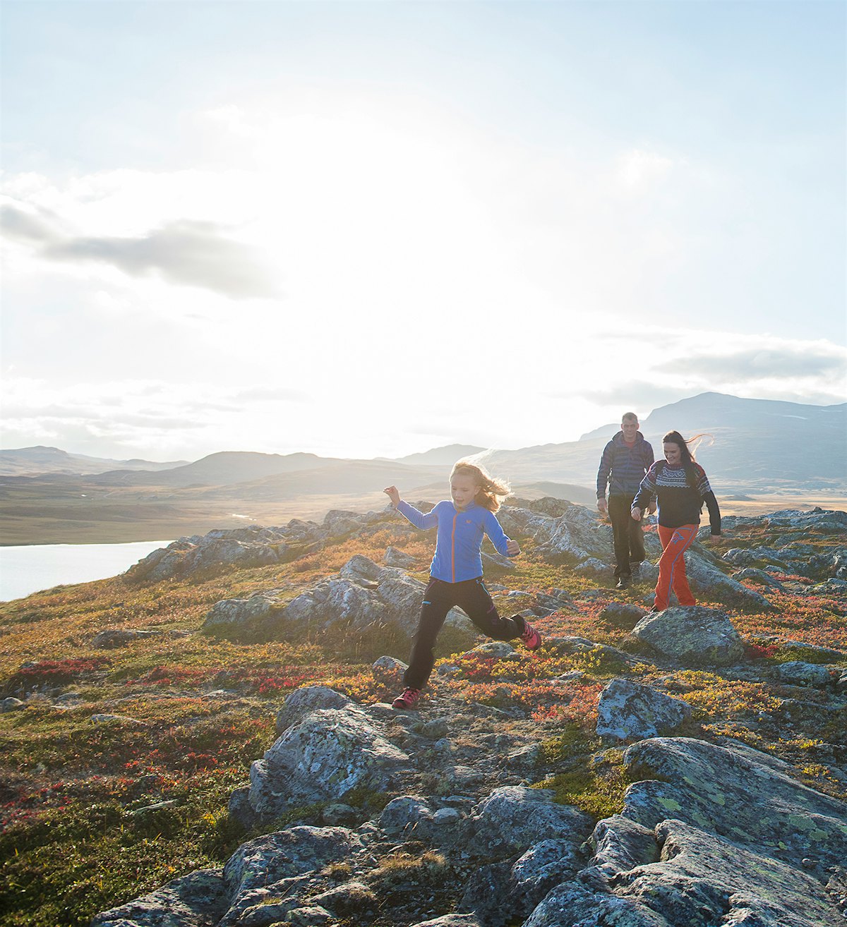 Familie på tre går på fjellet om høsten. Foto