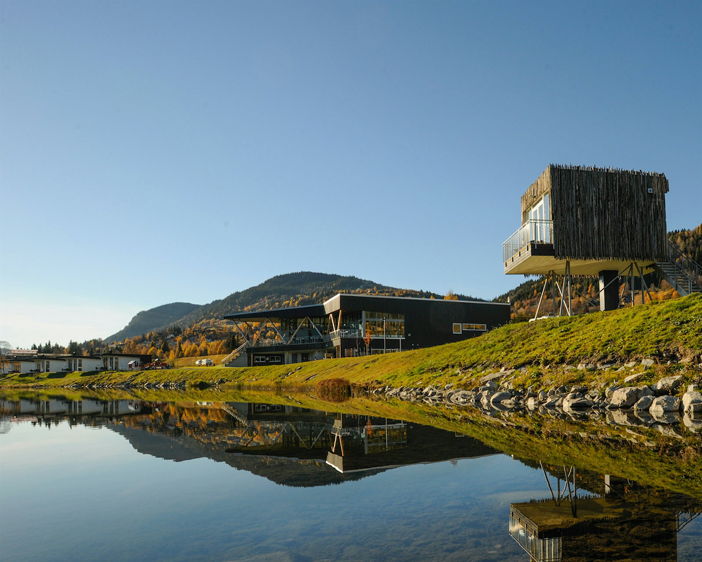 The cabins at Topcamp Hallingdal are located along the river, with the stilt cabin first, in autumn. Photo