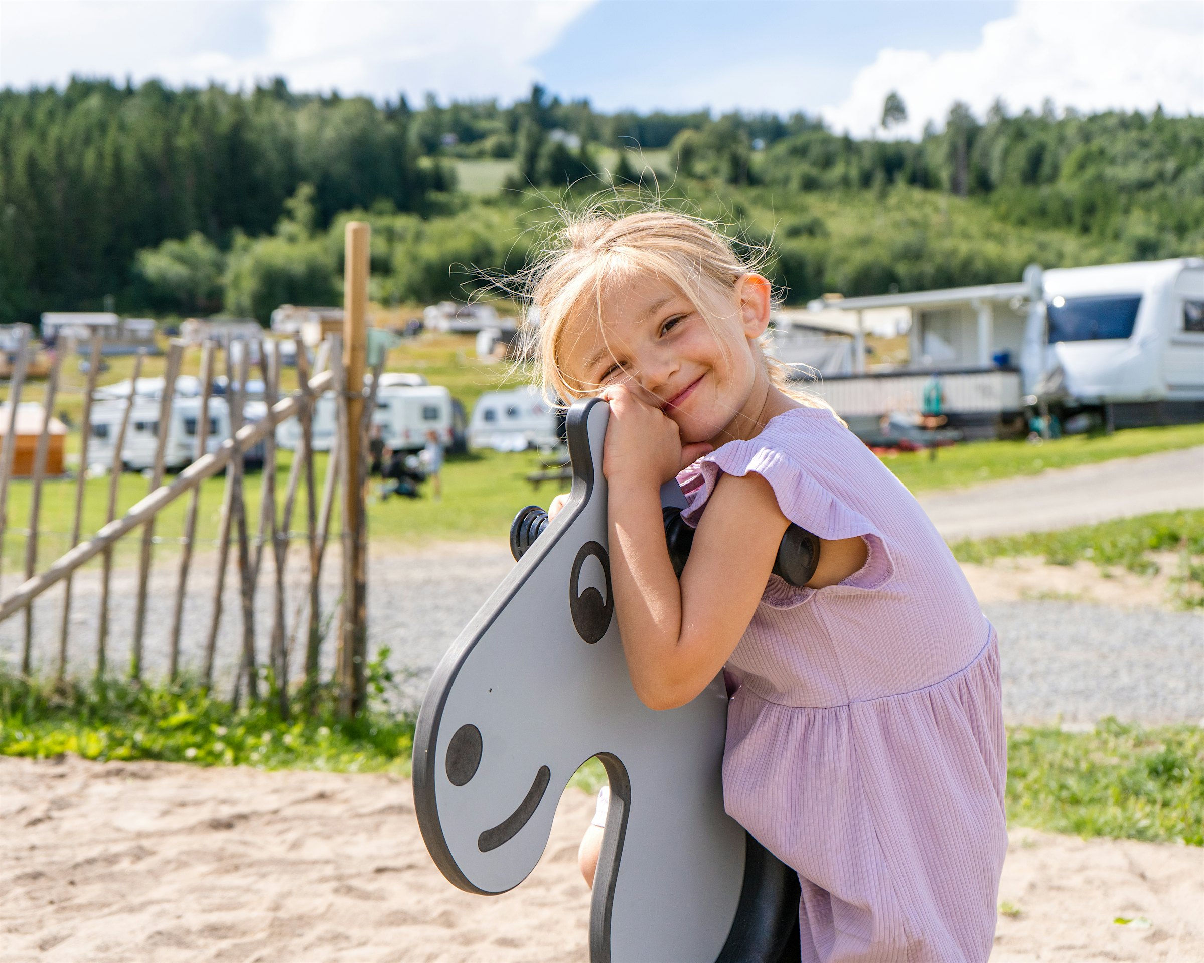 Girl plays on a playground with a campsite in the background. Photo