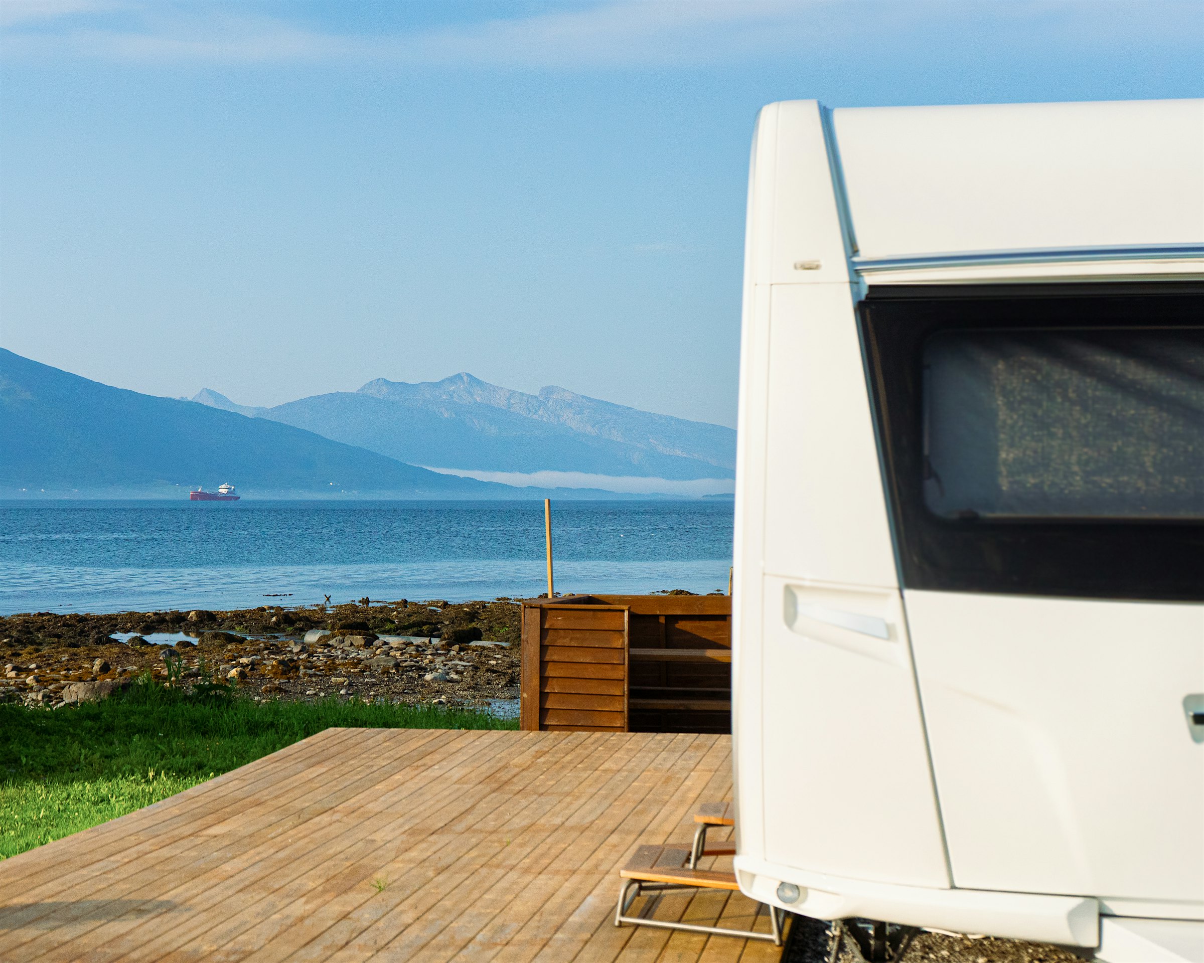 Caravan front with wooden cladding outside. View to sea and mountains. Photo