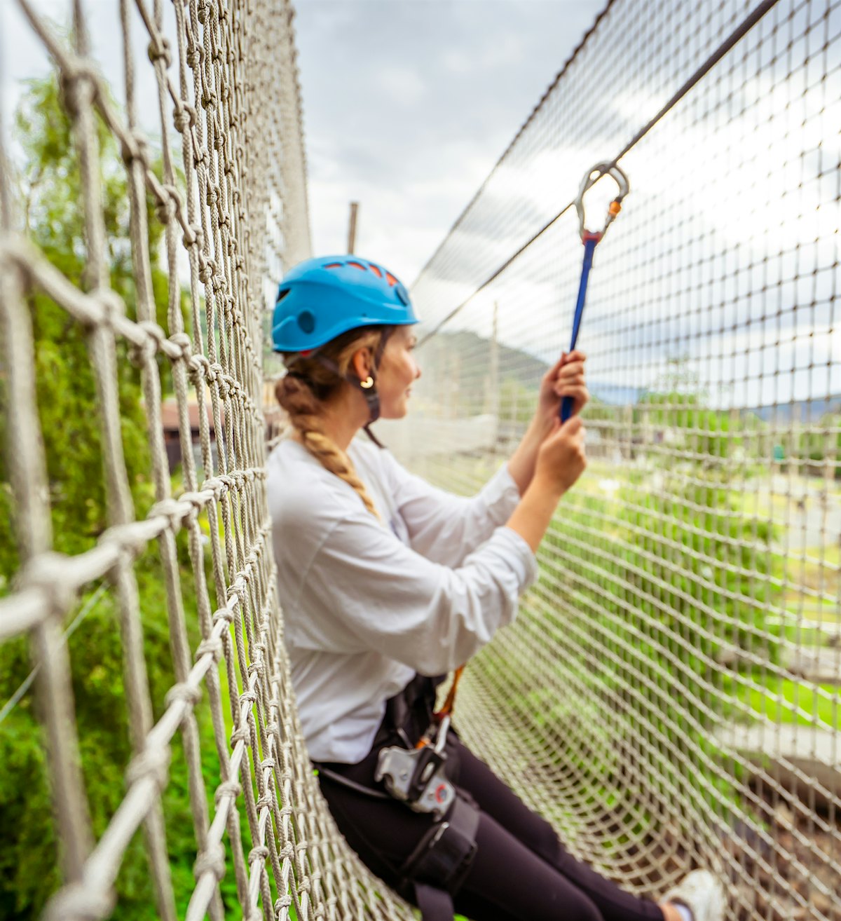 Mädchen lehnt an einem Netz im Kletterpark von Topcamp Hallingdal und schaut hinaus. Foto