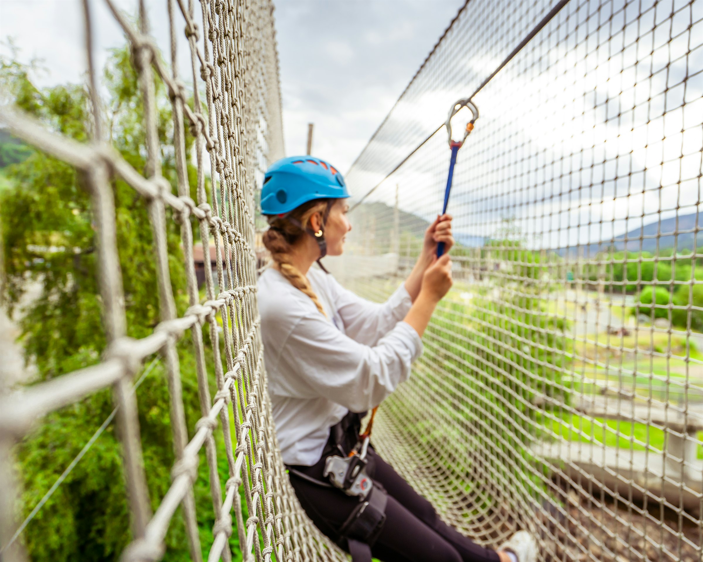 Jente lener seg i et nett i klatreparken hos Topcamp Hallingdal og ser utover. Foto