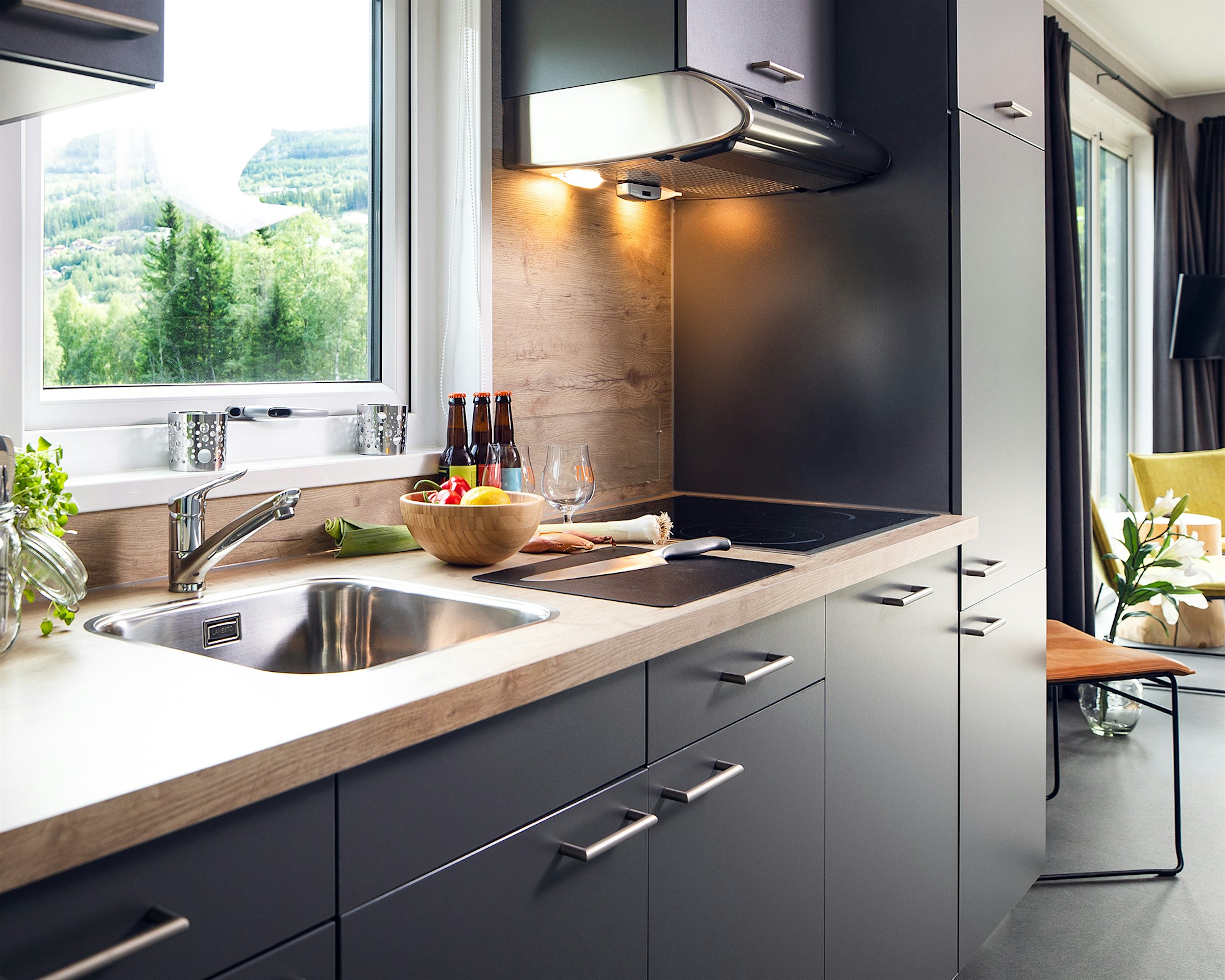 Lyst, moderne kjøkken med benkeplate i tre og svarte fronter. Foto