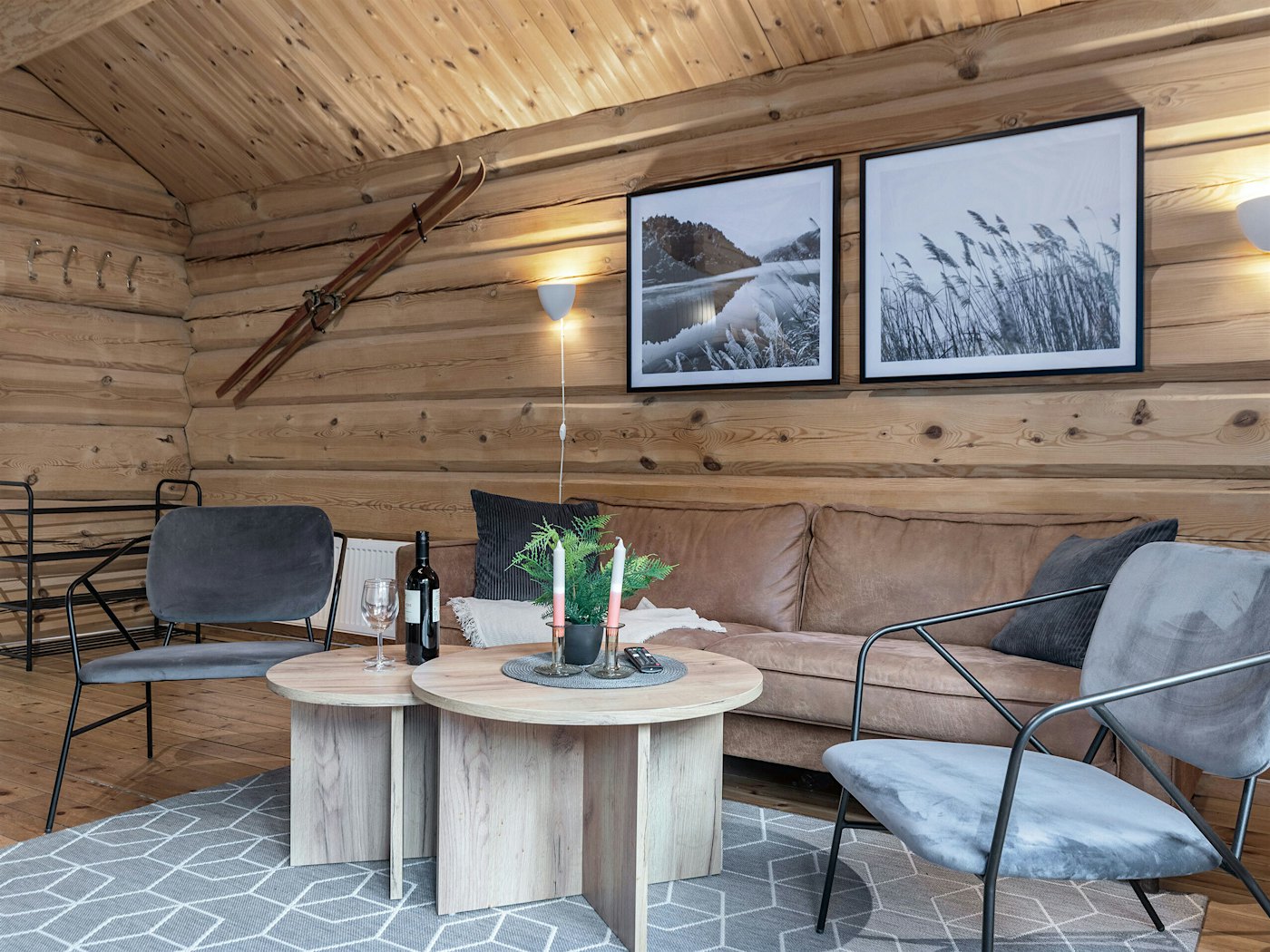 Trefarget stue moderne innredet med sofa, stuebord og stoler. To store bilder og et par ski på veggen.
