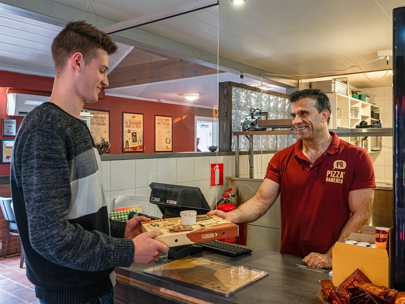 Servitør leverer takeout-pizza til kunde.
