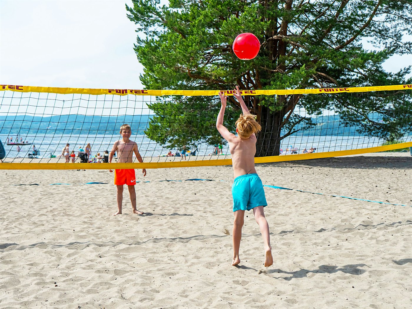 Two boys play volleyball on the beach. Photo