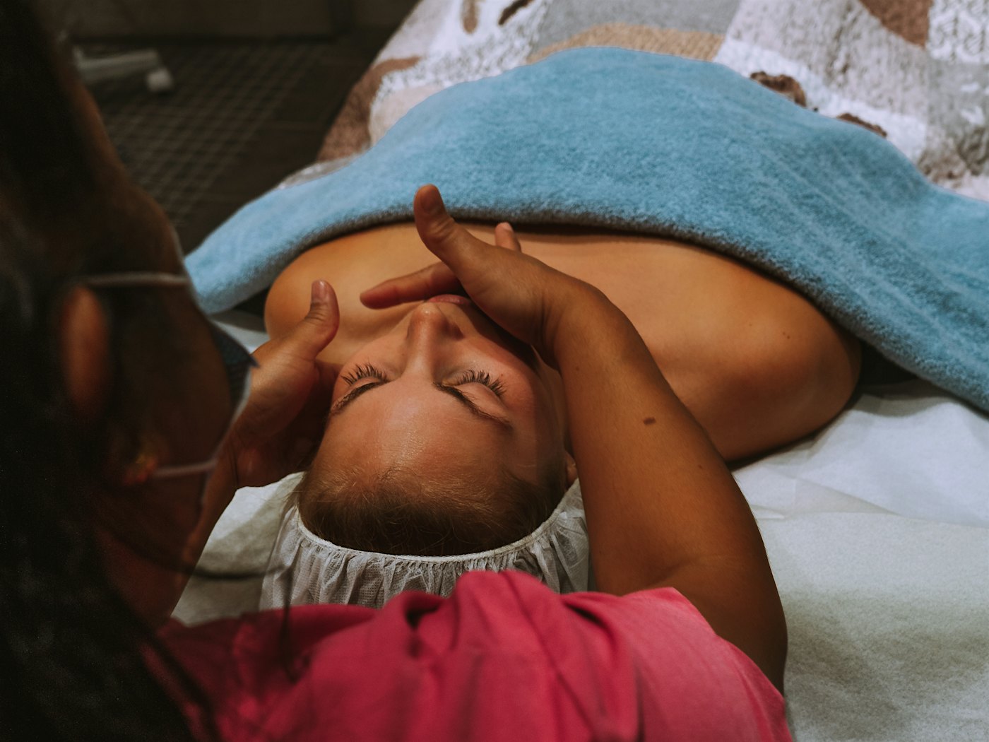 Mädchen liegt auf einer Massagebank und erhält von einem Masseur eine Gesichtsmassage. Foto