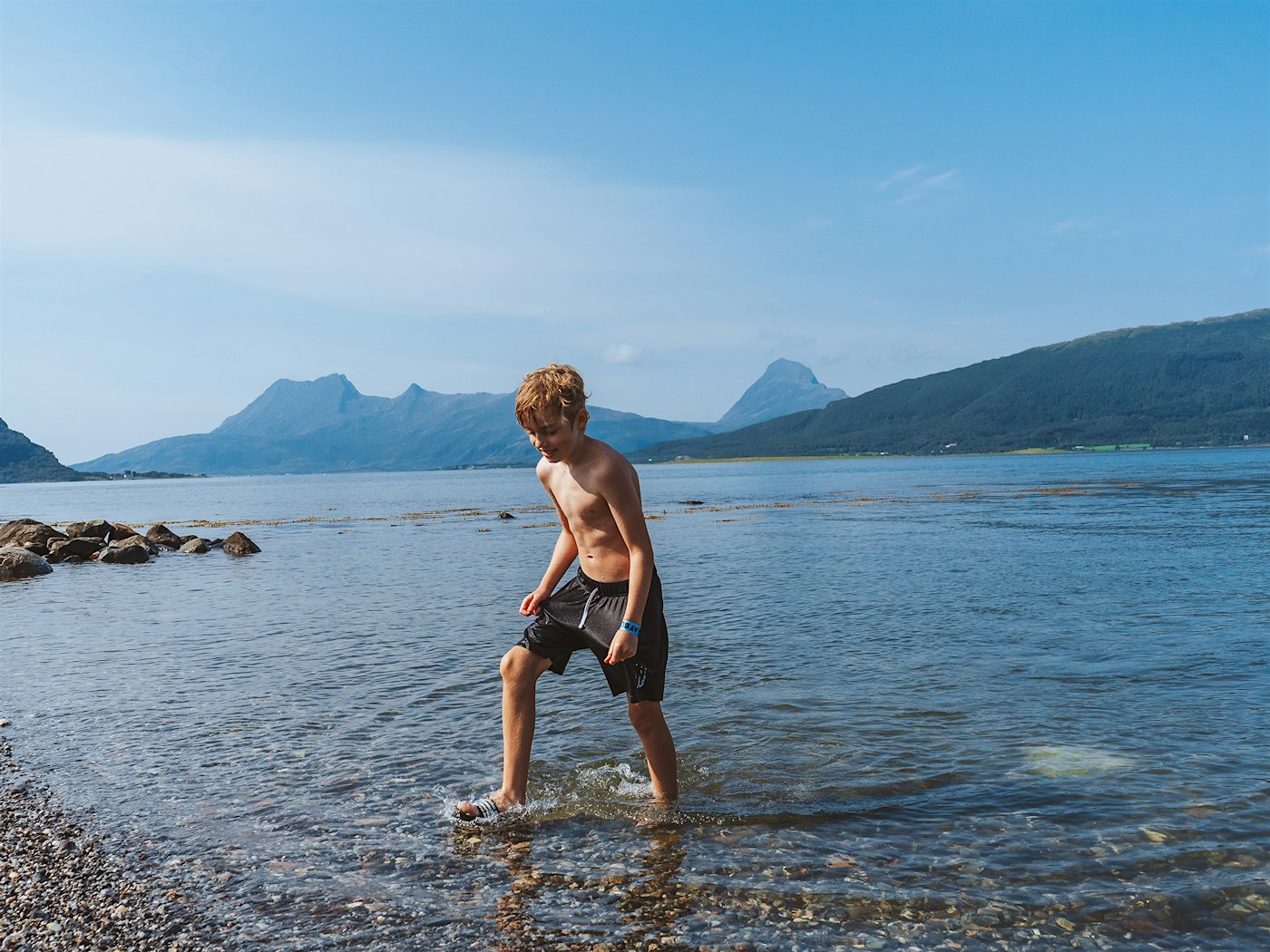 Boy bathing in the sea with mountains in the background. Photo