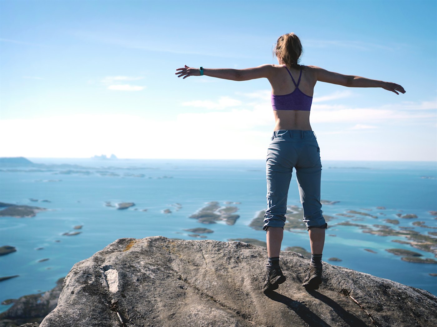 Mädchen steht mit ausgestreckten Armen auf einem Berggipfel und blickt auf die Aussicht. Foto