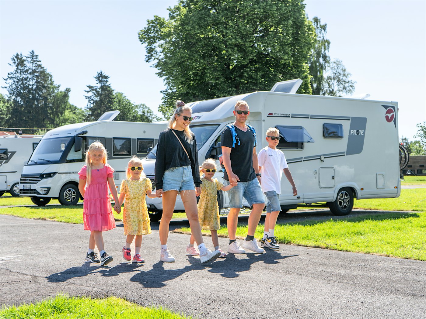 A family of five walks in front of motorhomes at Bogstad