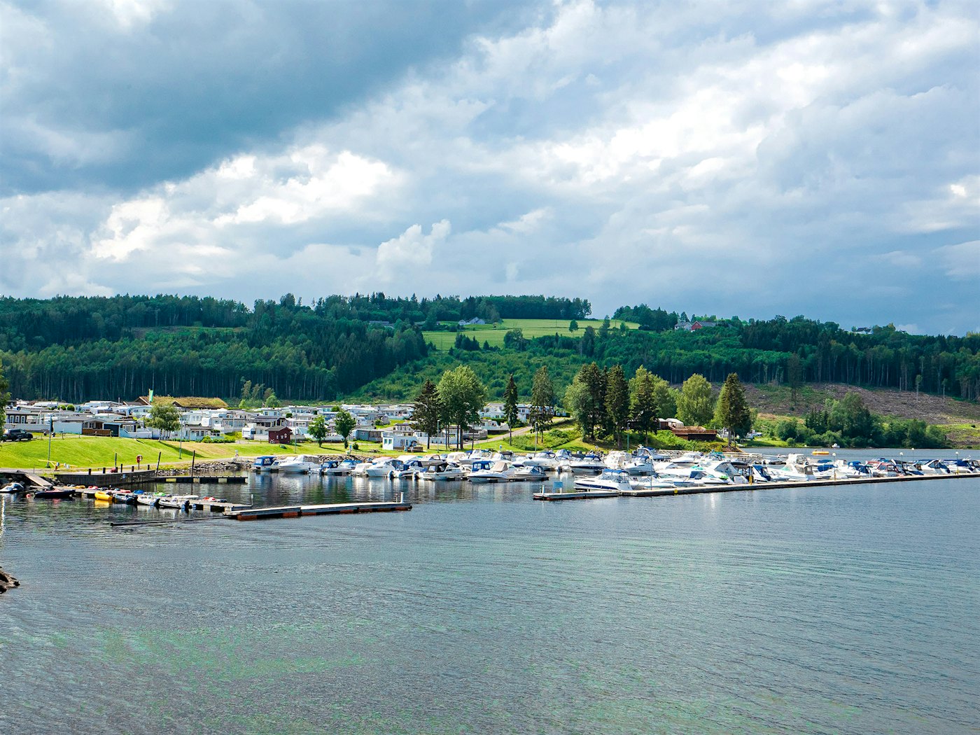 Übersicht über den Campingplatz mit dem Jachthafen im Vordergrund und dem Wald im Hintergrund. Foto