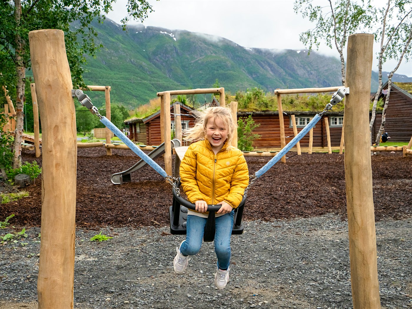 Girl remembers on playground, with mountains in the background. Photo