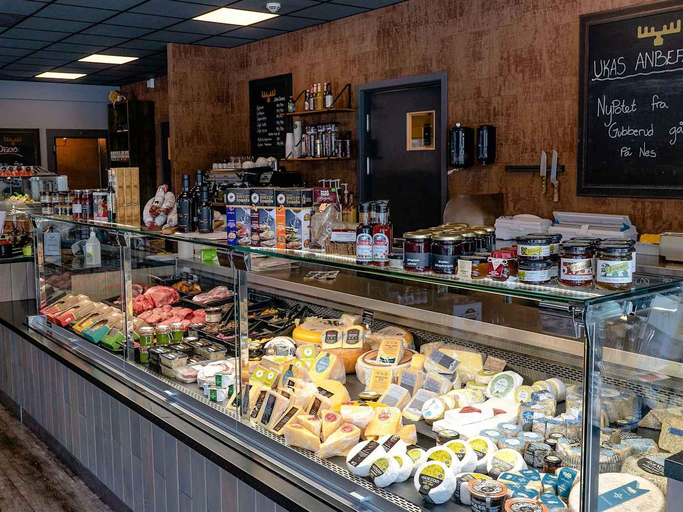 Fresh produce counter full of cheeses and various meat products, at Matfatet in Brumunddal. Photo