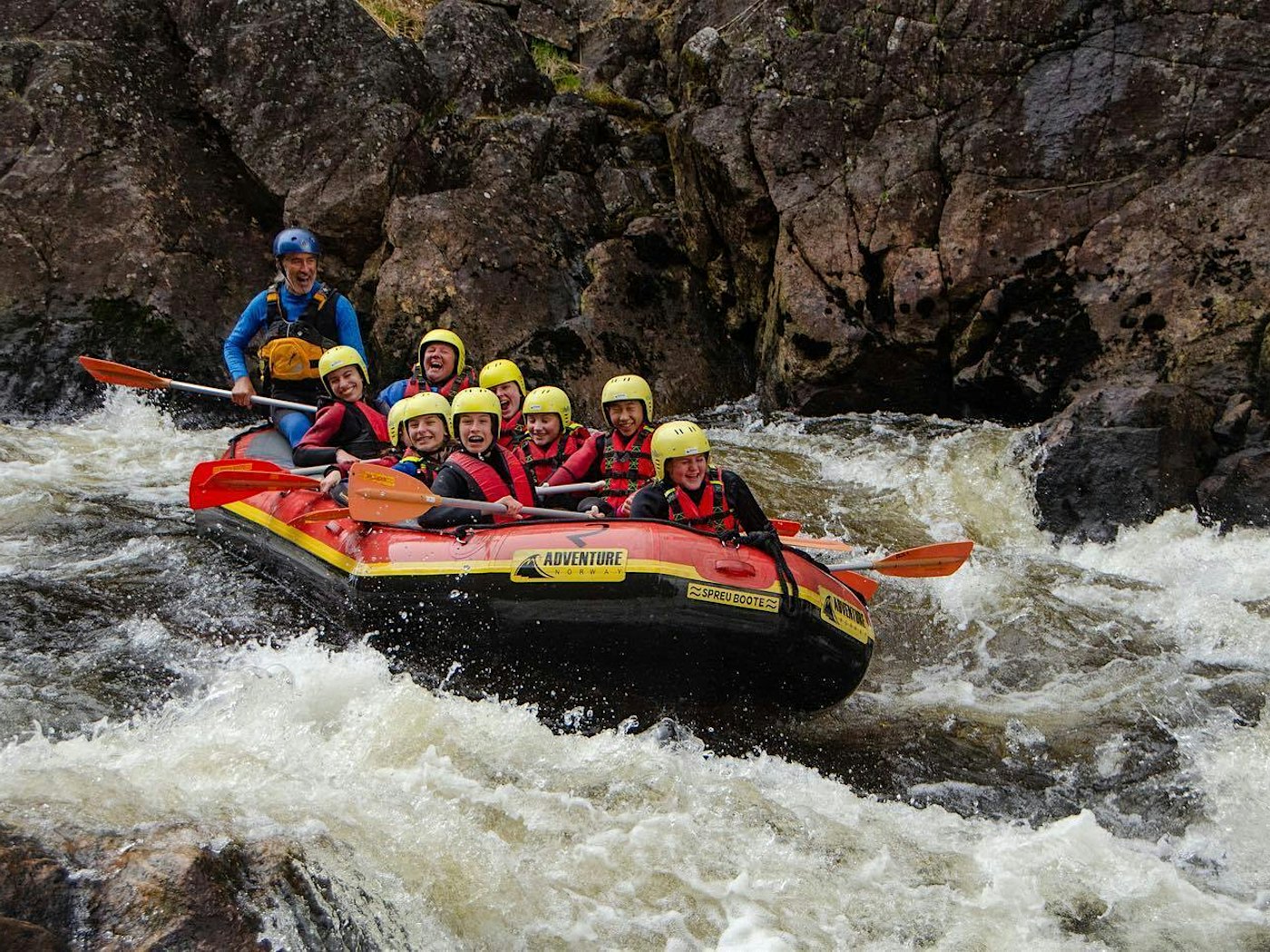 Eine Gruppe raftet mit einem Boot einen Fluss hinunter. Alle lachen und amüsieren sich. Foto