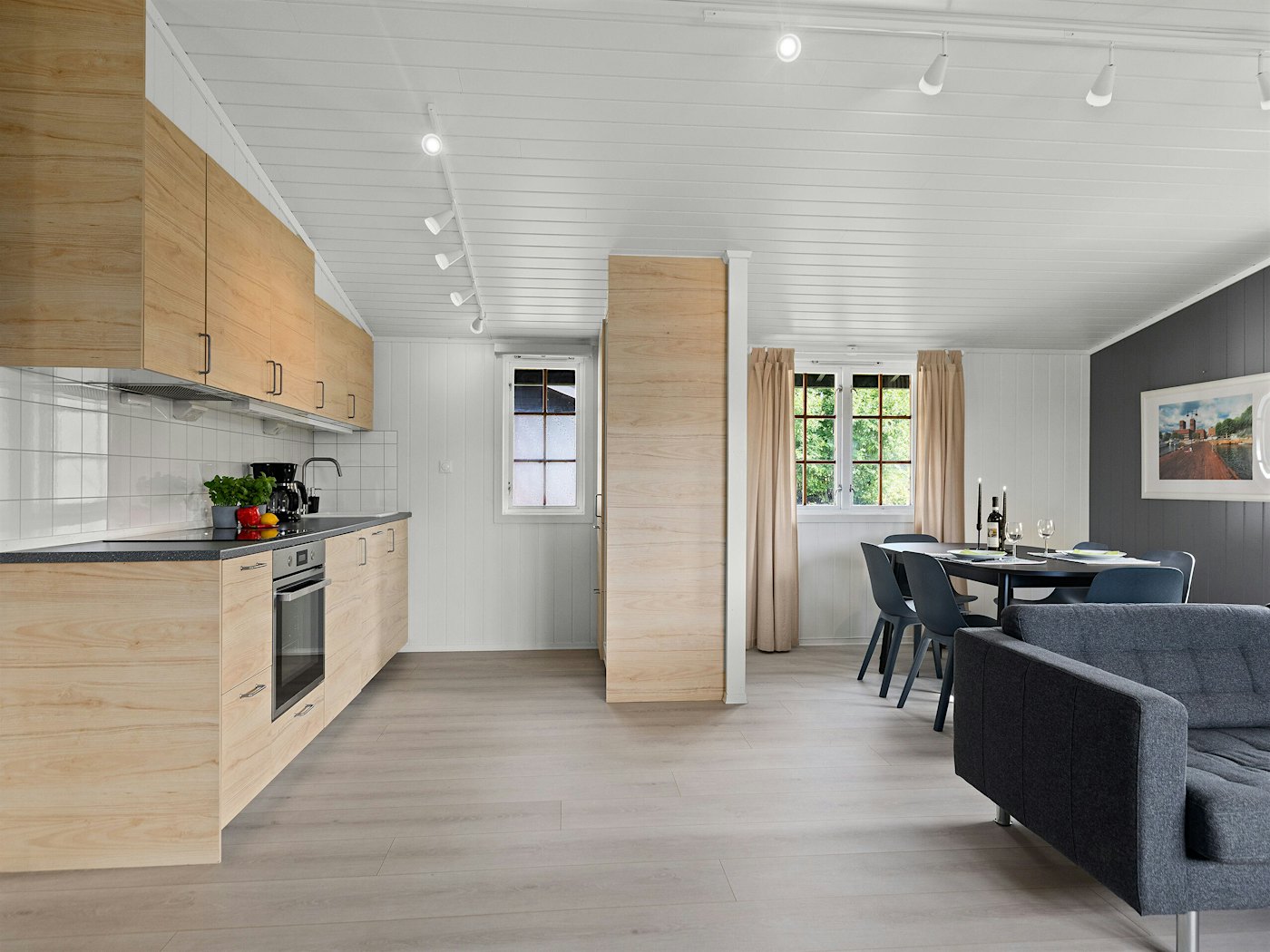 Moderne rom med kjøkken, spisegruppe og sofa. Foto