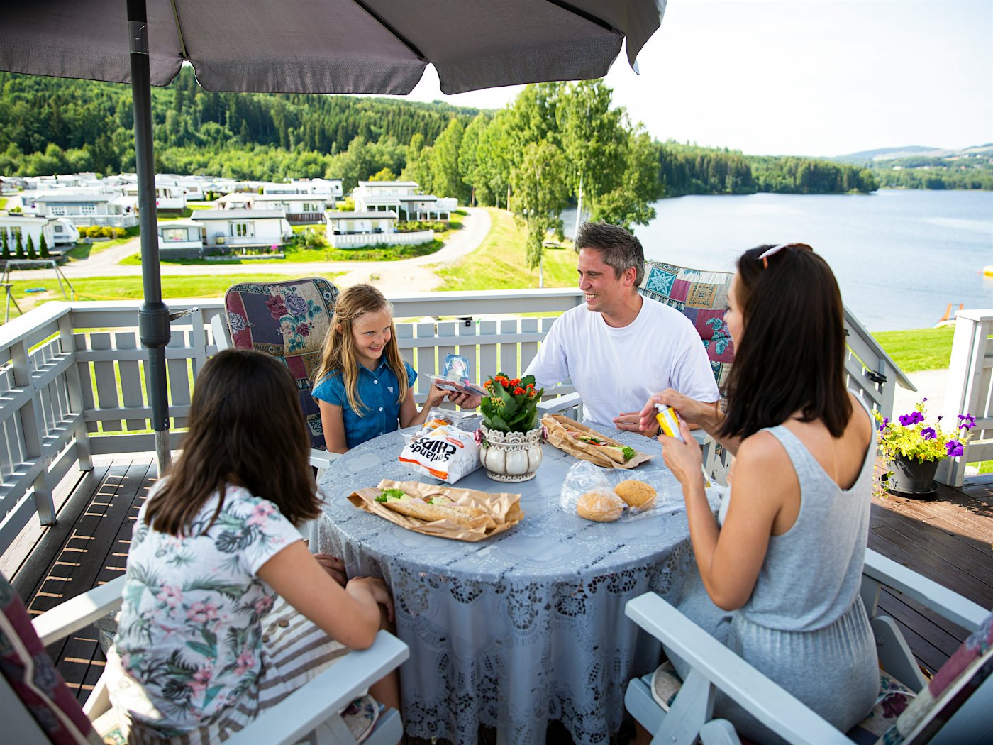 Familie spiser lunsj på camping sesongplass terrasse med utsikt til Mjøsa
