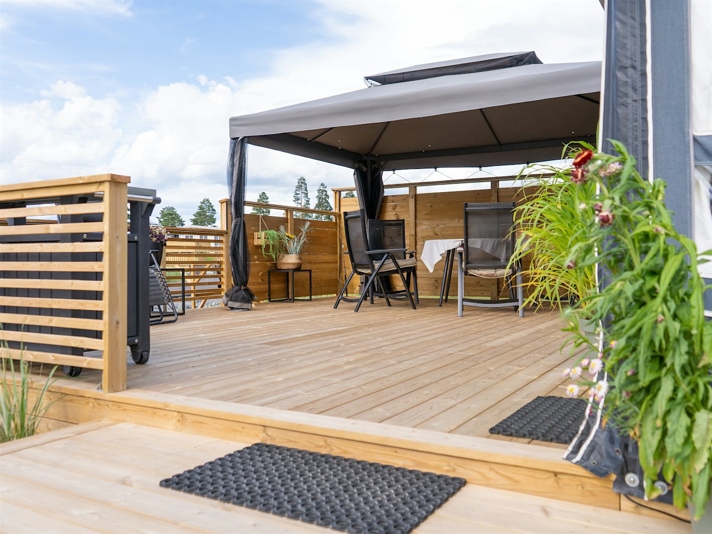 Terrasse tilhørende fastplass på campingplass. Utemøbler og planter på plattengen. Foto