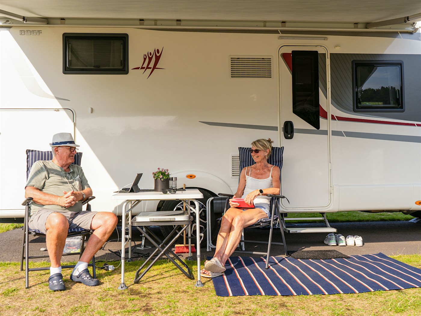 Man and woman relaxing in front of motorhome. Photo