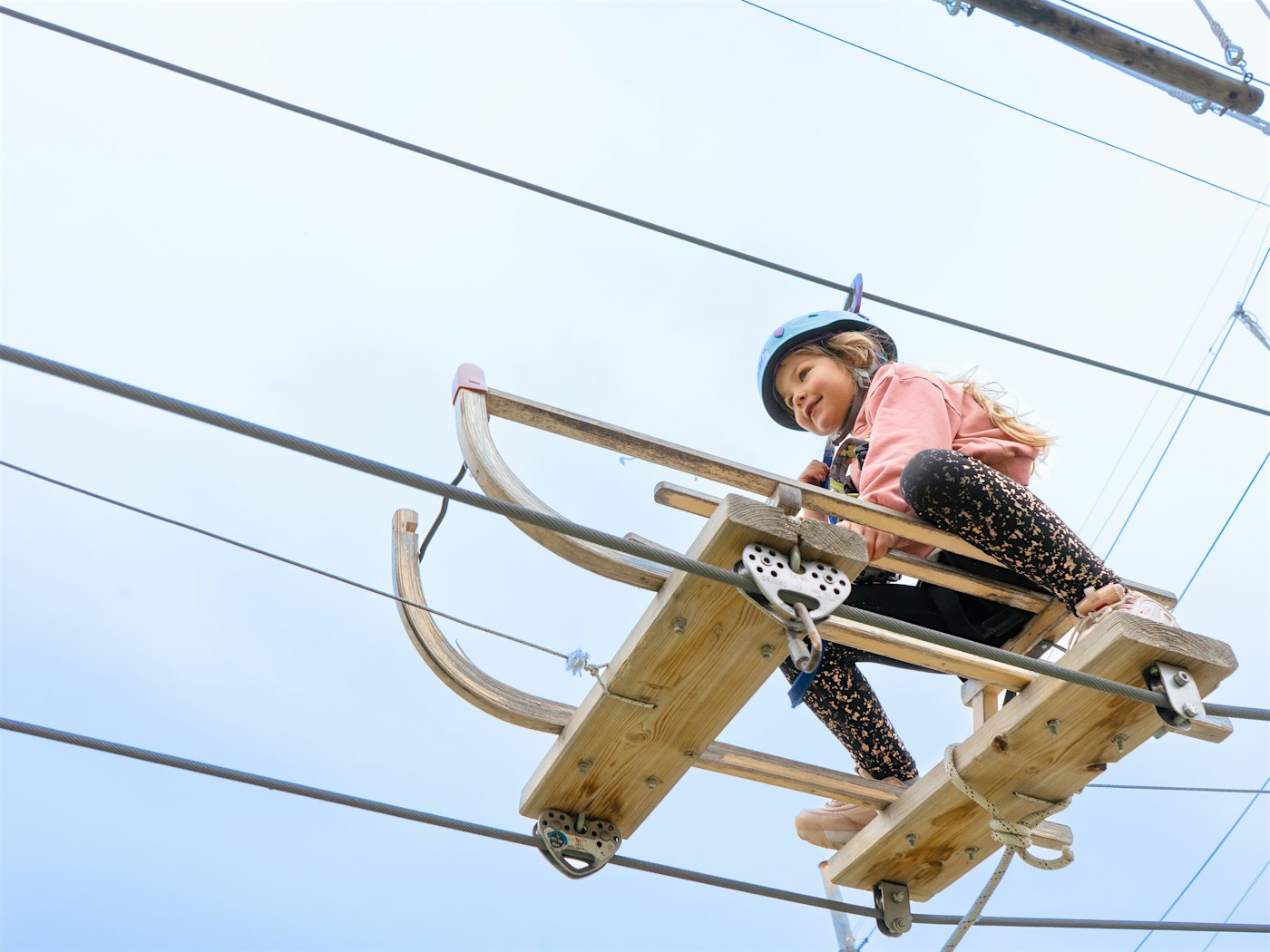 A girl has fun while sitting on a toboggan zipline in the climbing park. Photo