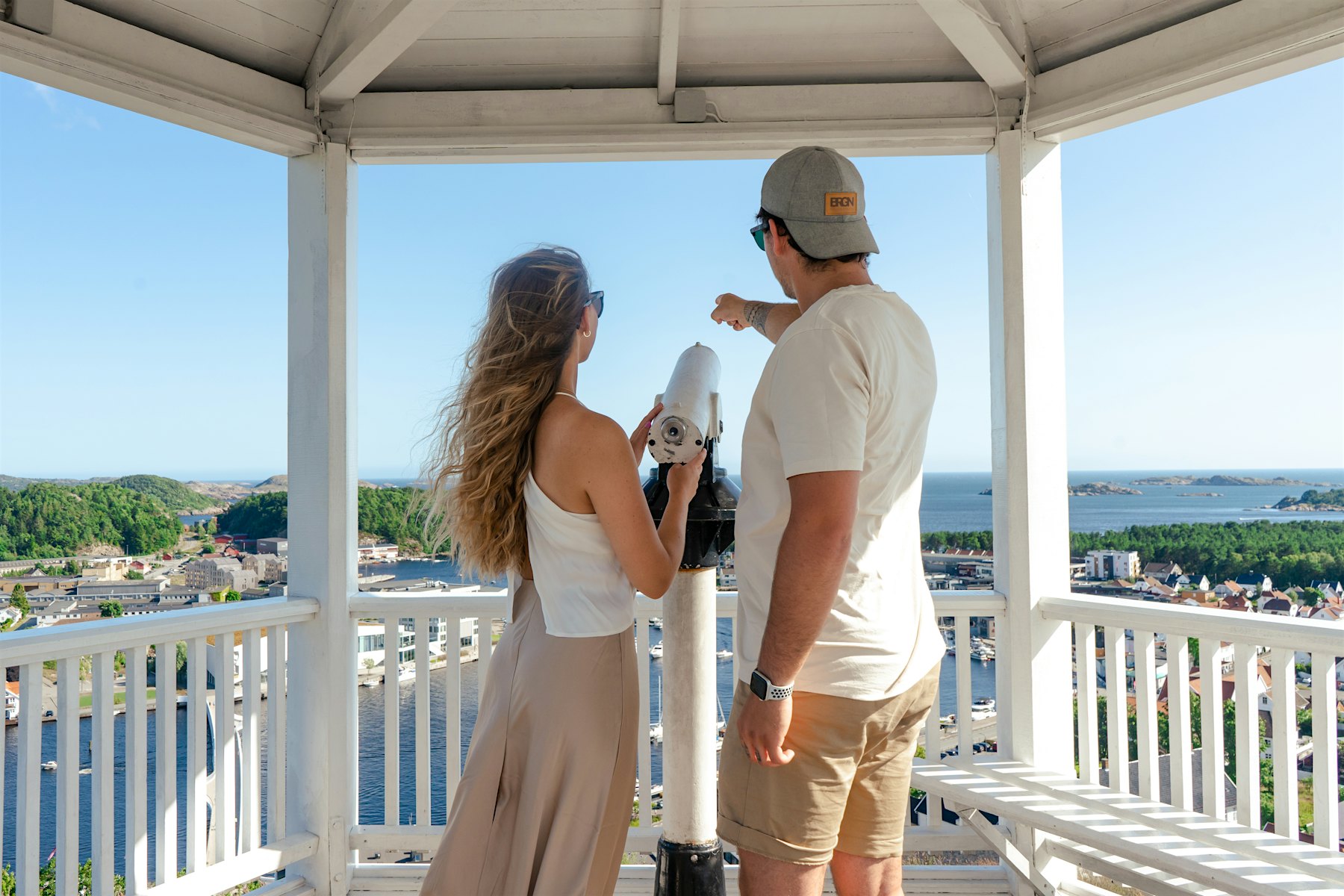 A girl and a boy stand by a pair of binoculars in a telescope house and look out over the horizon into the sea. Photo