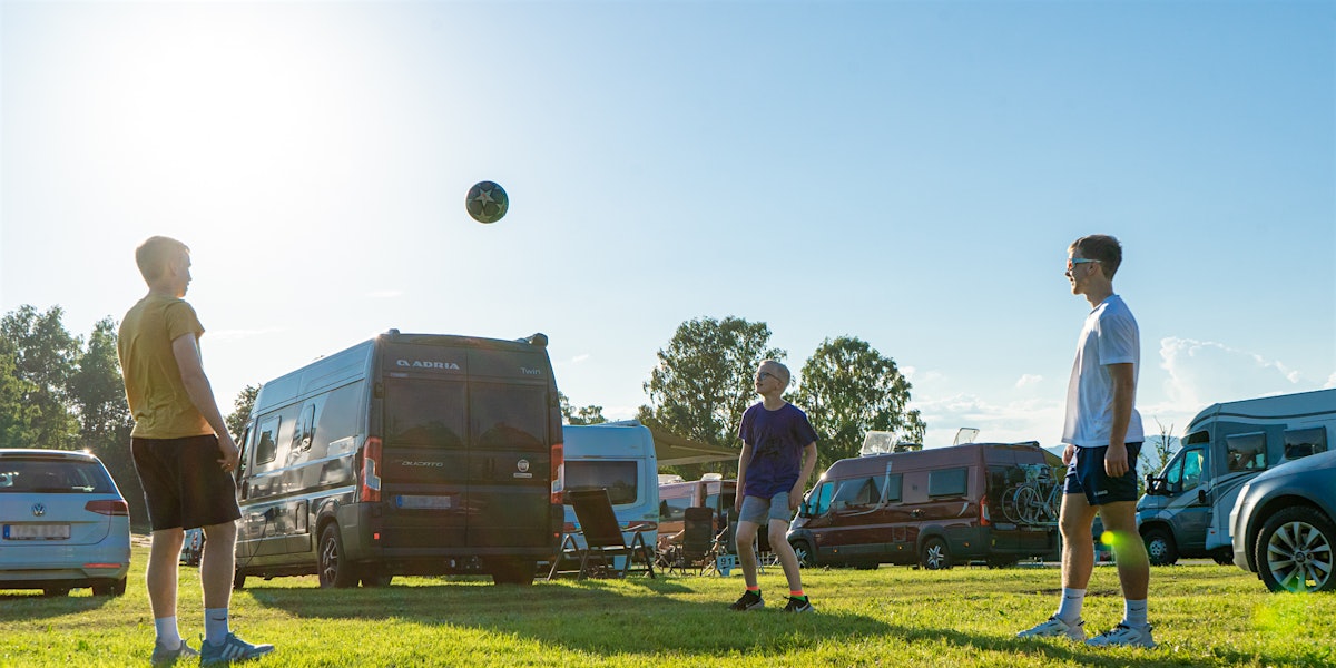 Drei Jungs spielen auf einem Campingplatz Fußball. Foto