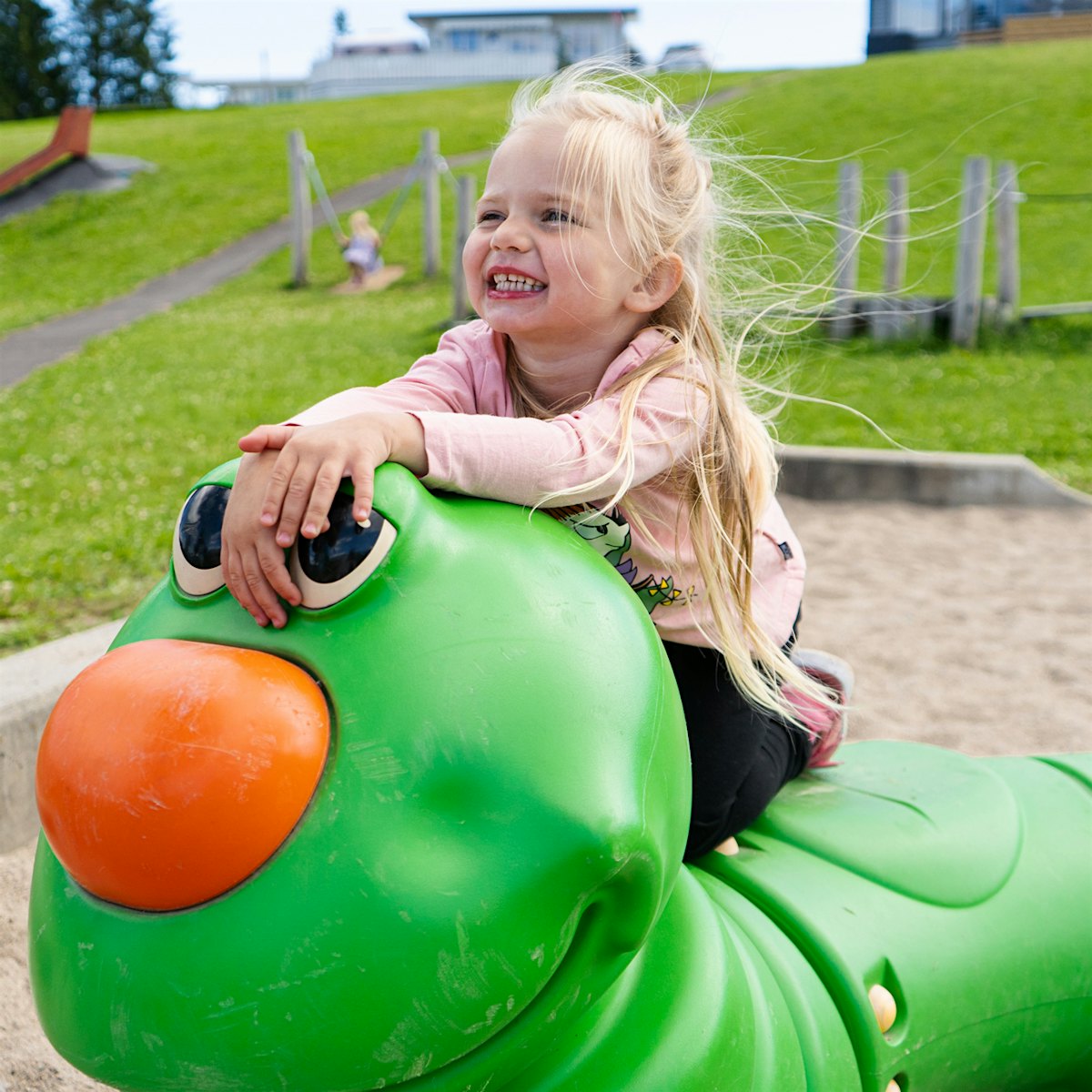 Girl on toy caterpillar on playground. Photo
