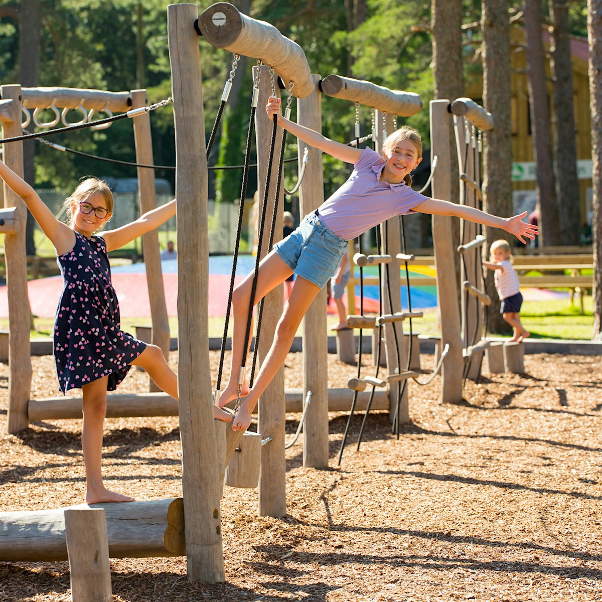 Two girls play in the climbing frame on the large playground at Topcamp Sjøsanden. Photo