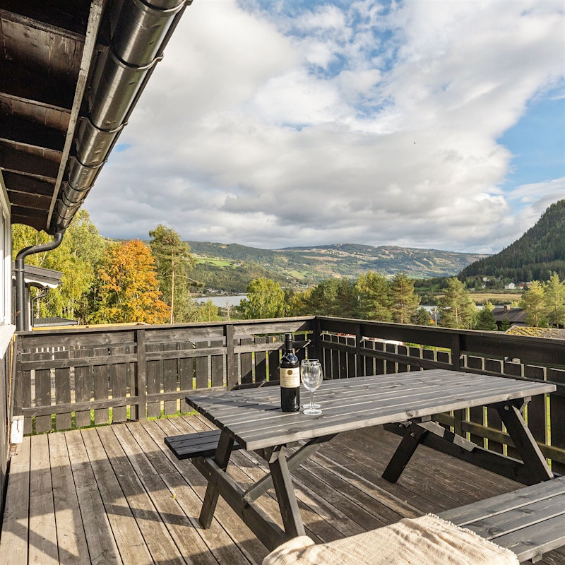 Stor veranda med sittebenk, utsikt over fjell og vann. Foto
