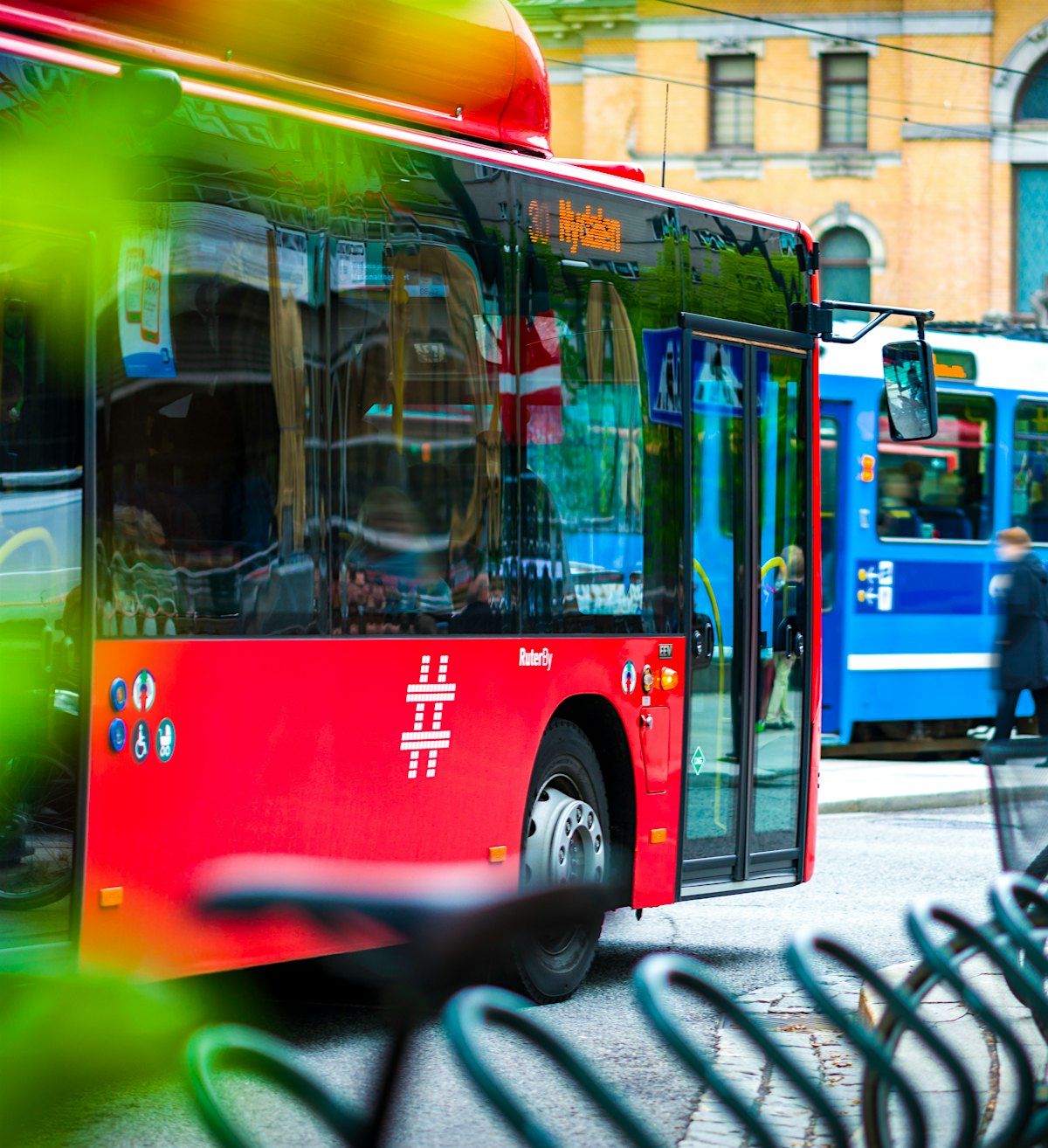 Rød buss, bak en blå trikk